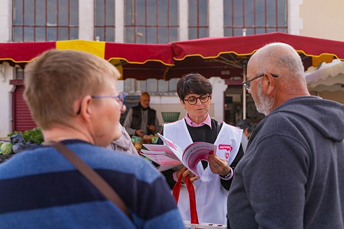 Une agent de la Région présente une plaquette d'information à des passants