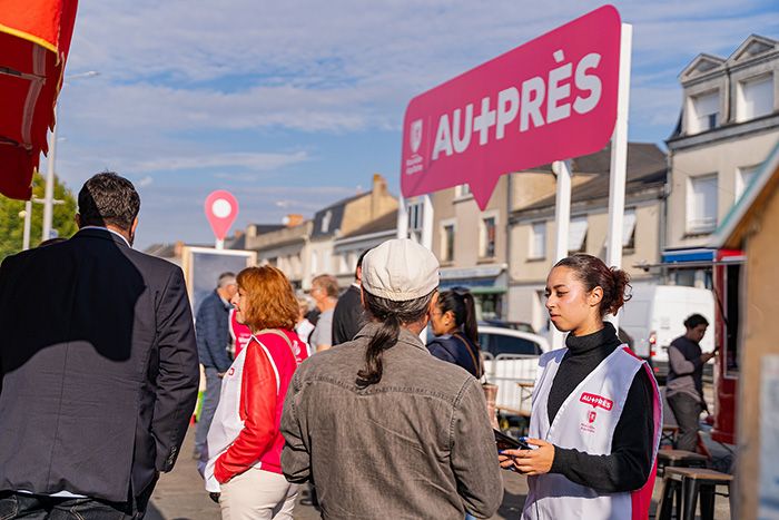 Deux agents régions dialoguent avec des passants devant le stand Au plus près